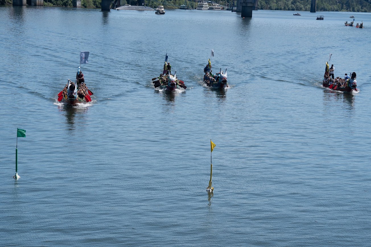 Traditional-Style Dragon Boats near the flags at the end of a race.